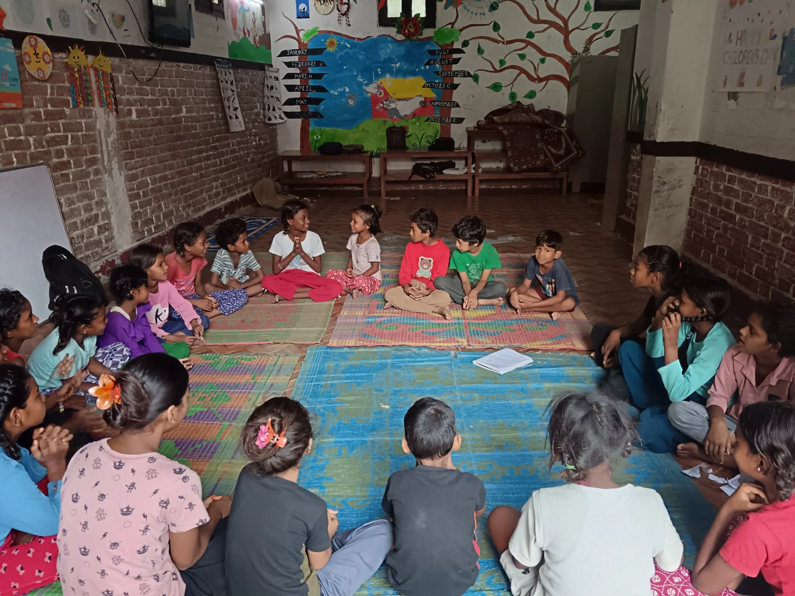 A Plan for Every Child Children sitting on mats in a classroom with a mural behind them