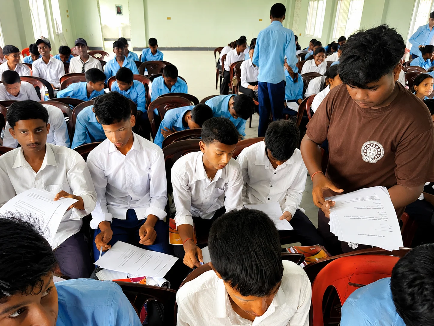 Students in white shirts sitting in rows during a school session