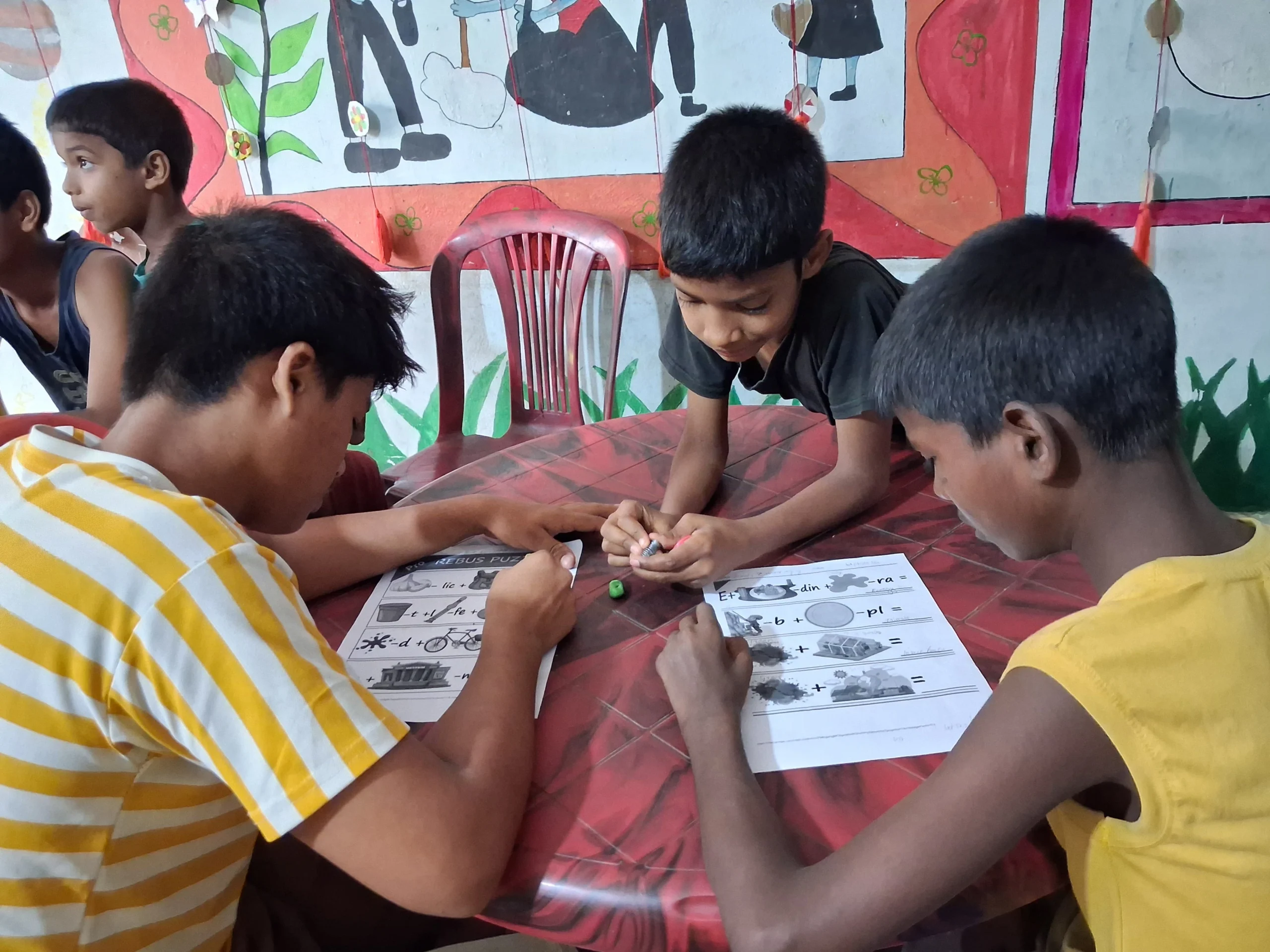Children filling in worksheets together around a table