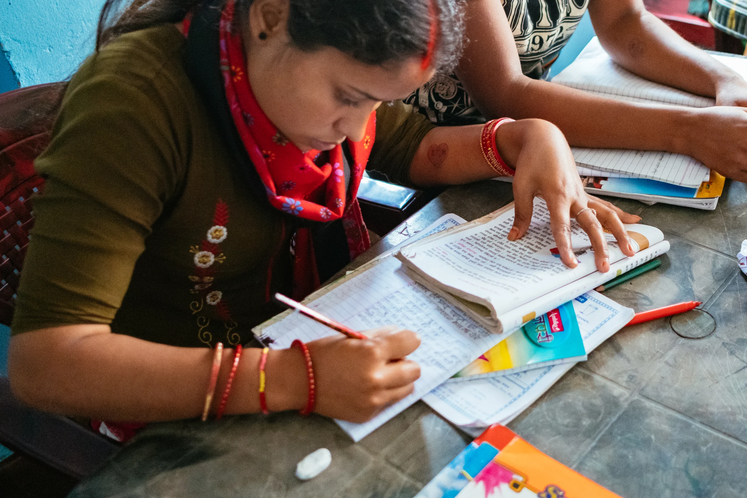 Girl in a red scarf studying with books and coloured pens