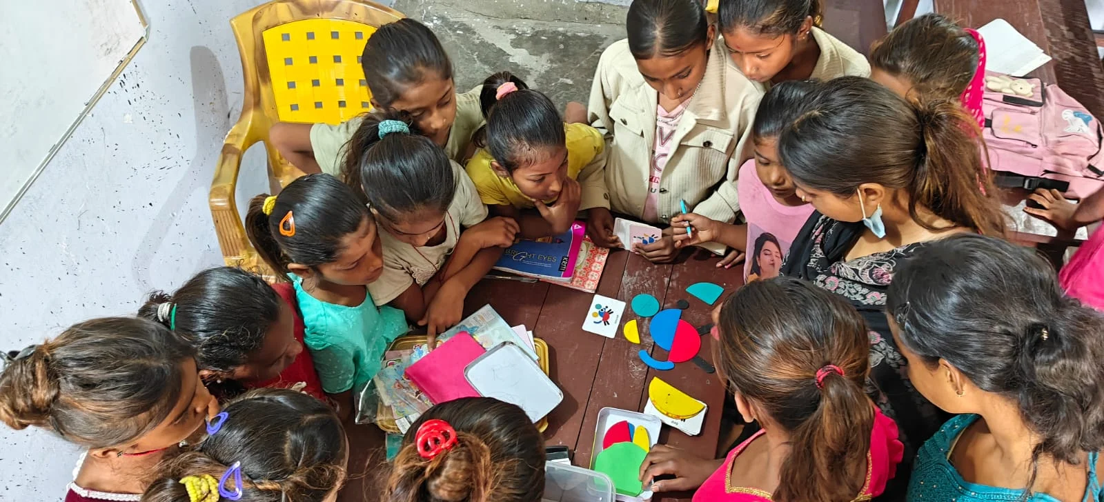 Young children drawing and playing together at a table, seen from above
