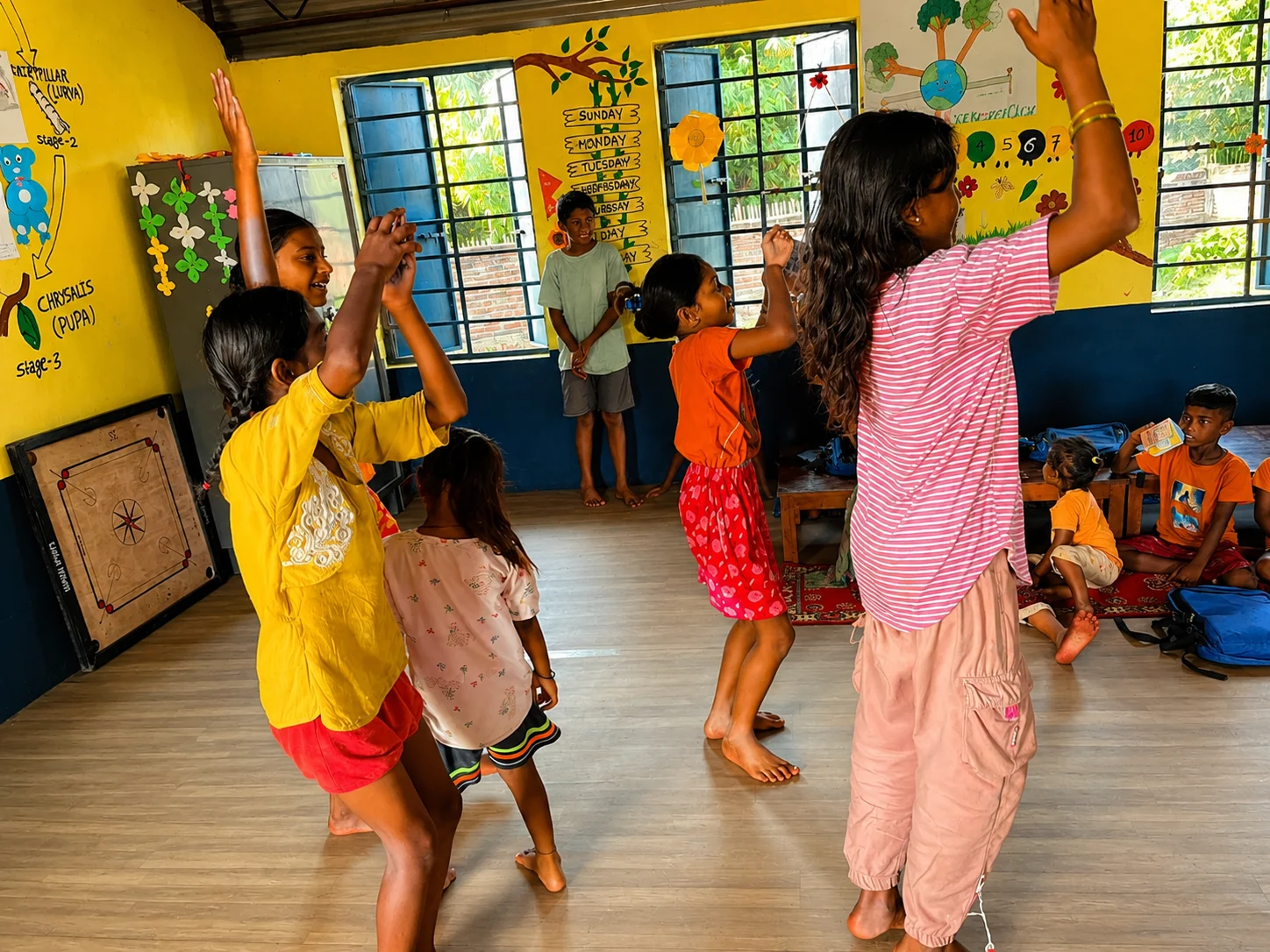 Children dancing and playing in a bright yellow classroom