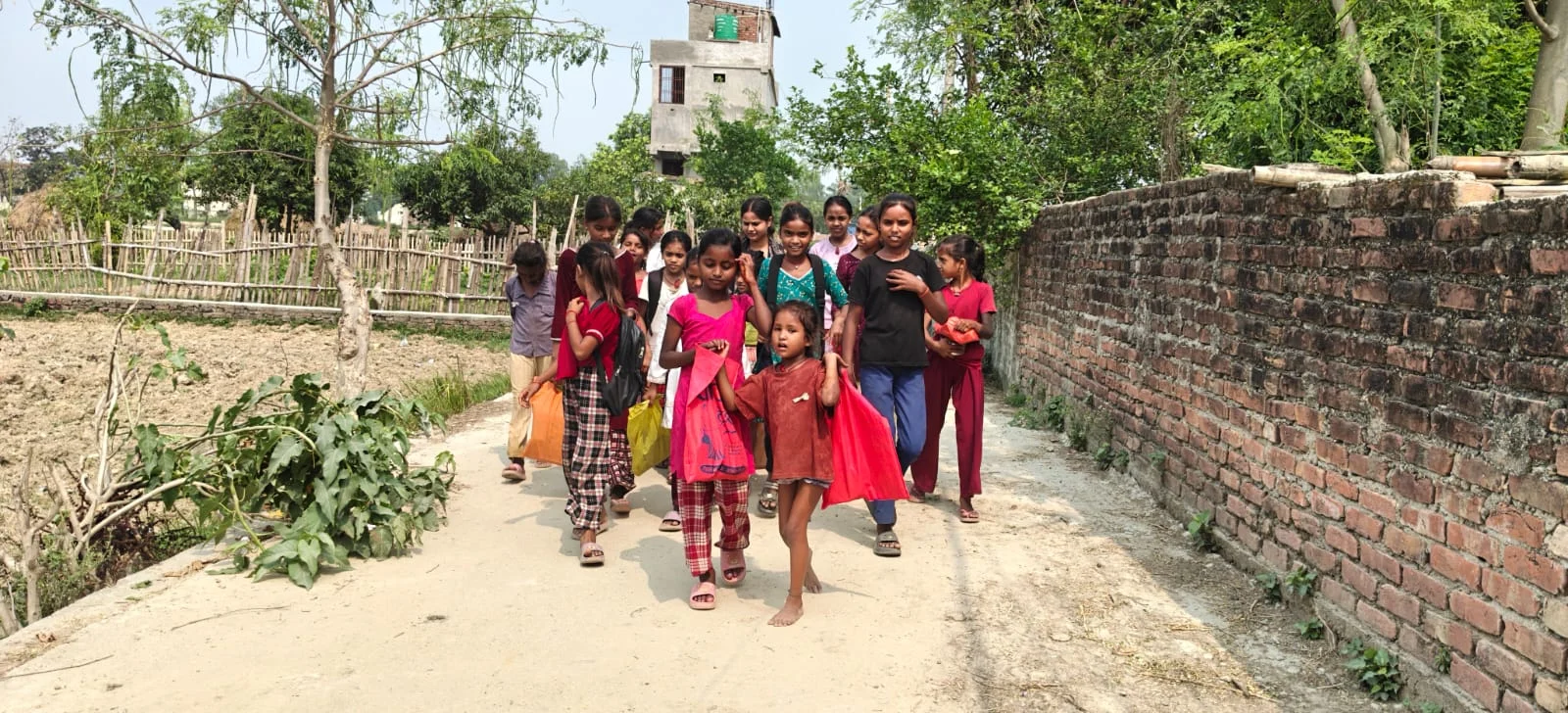 Group of girls in red tops walking along a village path