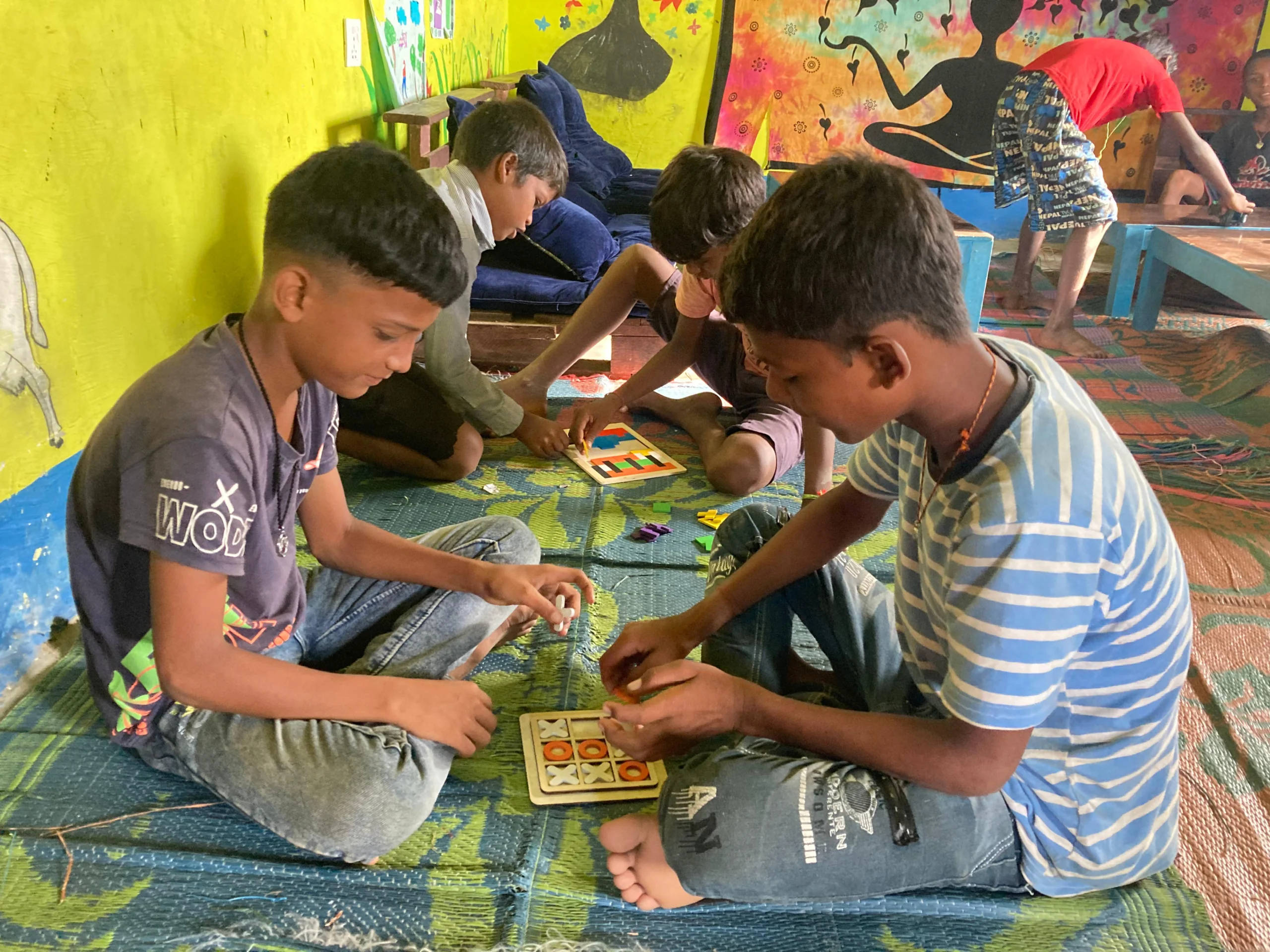 Families and communities are part of the story Two boys playing a board game on a mat