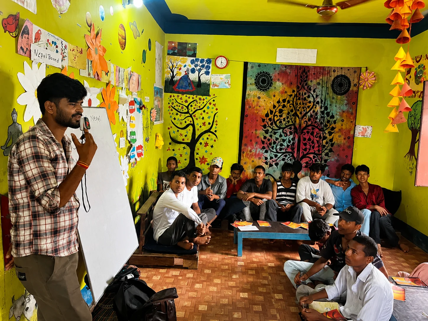 Trainer speaking to a seated group in a colourful community room