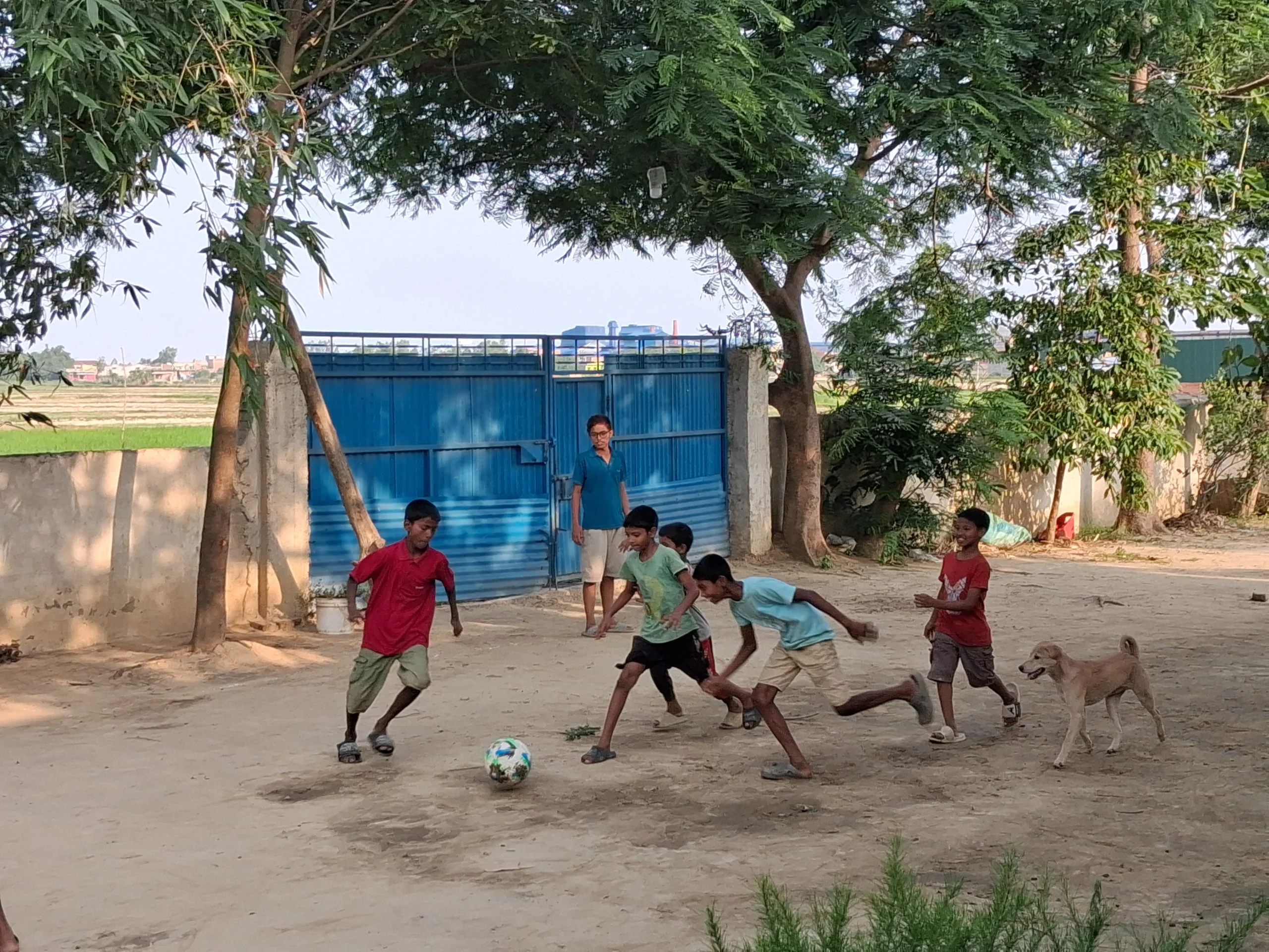 Children playing football on a dusty yard