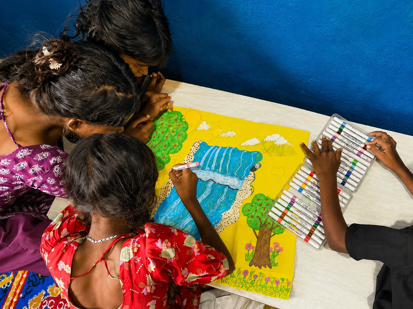 Children painting a colourful picture together on a table