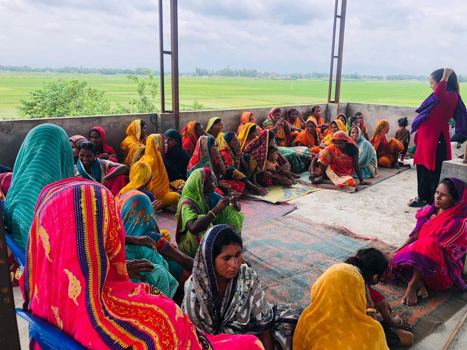 The start of something bigger Women and children sitting together on the floor at an outdoor gathering