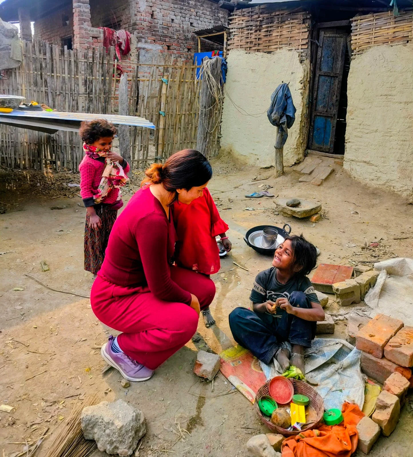 Working Together Woman crouching beside a child in a village yard