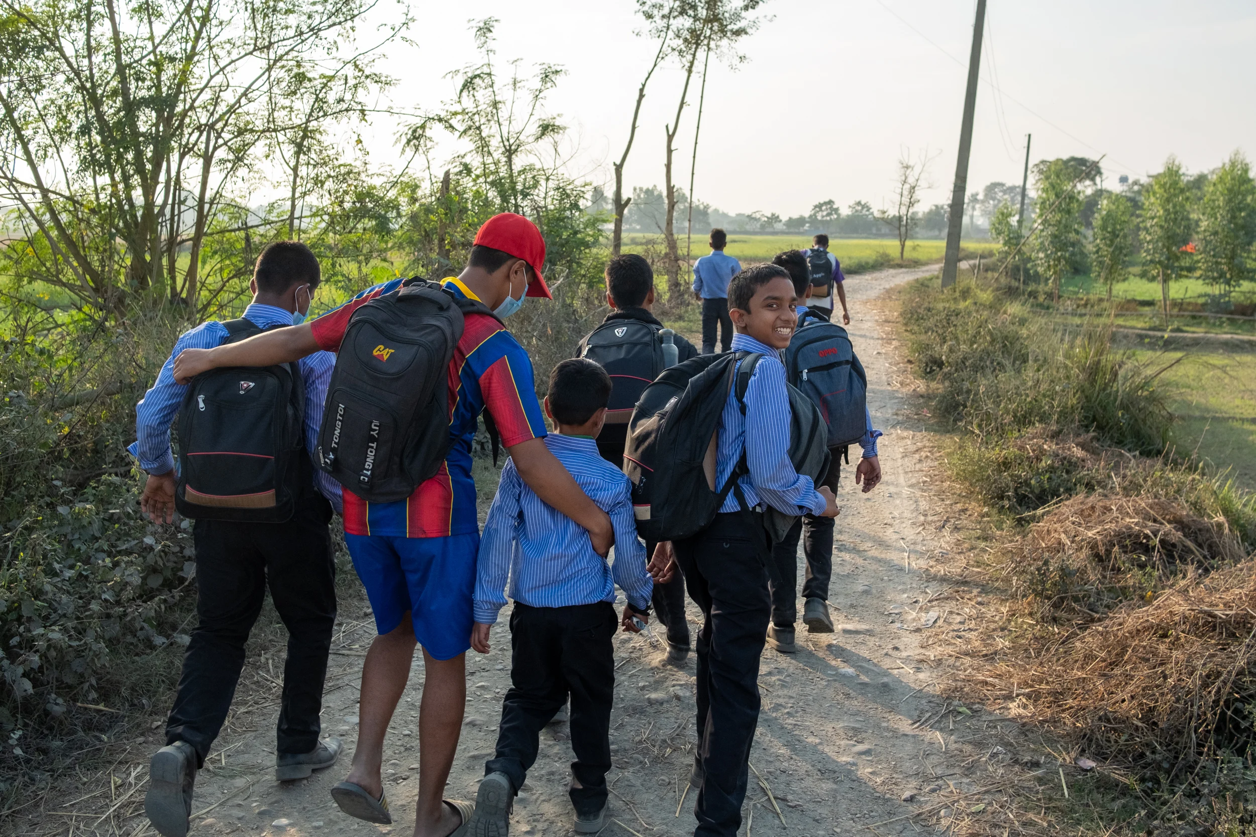 Working Together, Across Two Countries Children in school uniforms walking together along a village path