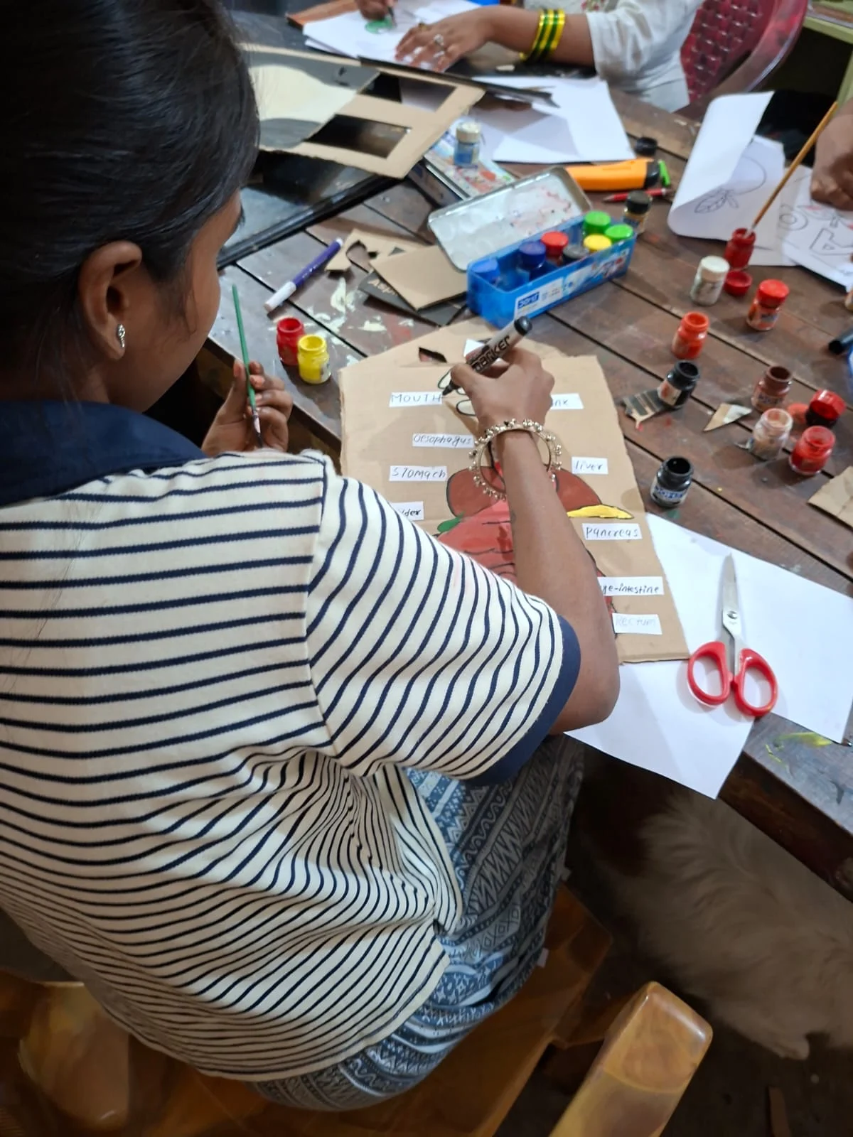 Girl in a striped top working with craft materials at a table